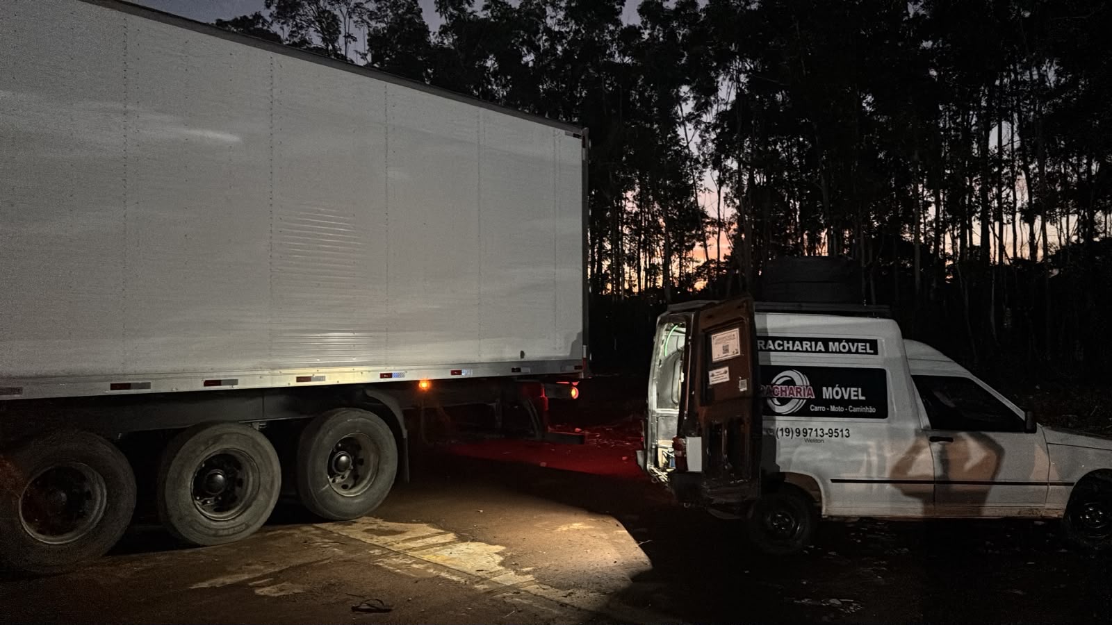 Técnico consertando pneu em rodovia à noite